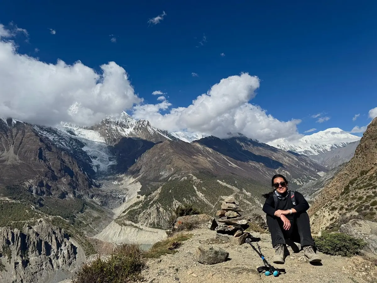 Trekker resting at a mountain viewpoint overlooking a glacier on the Annapurna Circuit