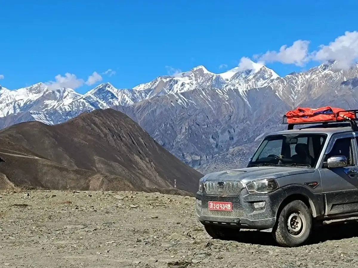 Jeep carrying rooftop luggage on a rocky road with snow-covered mountains on the Annapurna Circuit