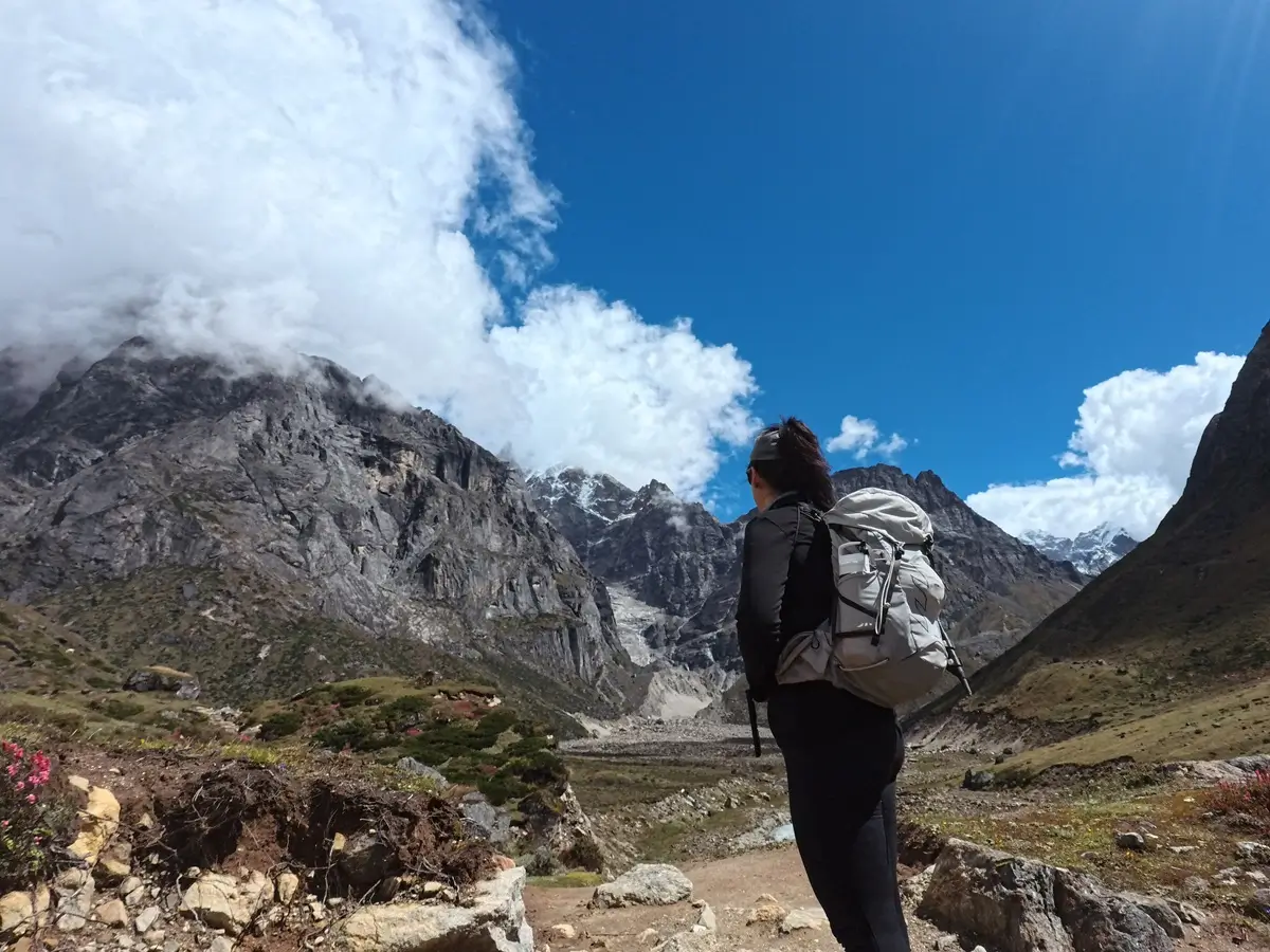 Trekker walking along a rocky trail in the Hinku Valley, surrounded by mountain slopes on the approach to Mera Peak.