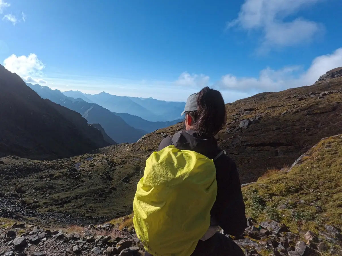Client overlooking layered mountain ridges from a rocky trail on the return from Mera Peak