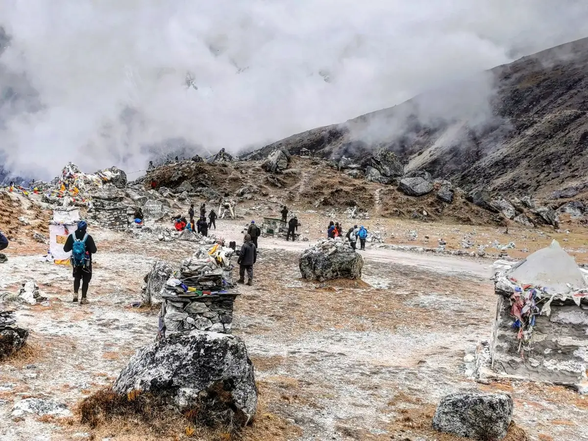 Trekkers walking among the memorials at the top of the Thukla climb
